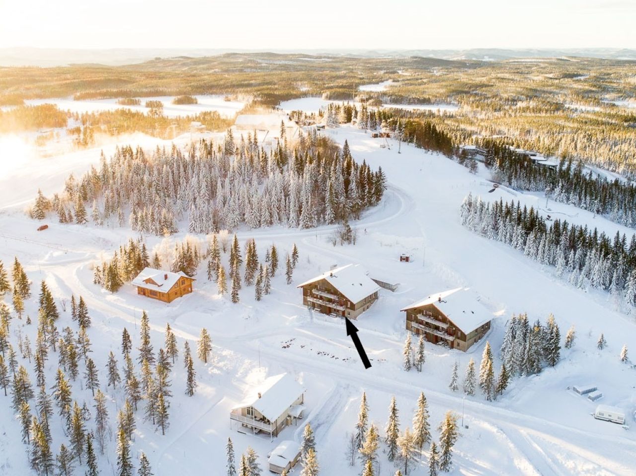 Flygbild över snötäckt landskap med stugor och skog i vintermiljö. Flygbild över snötäckt landskap med stugor och skog i vintermiljö.