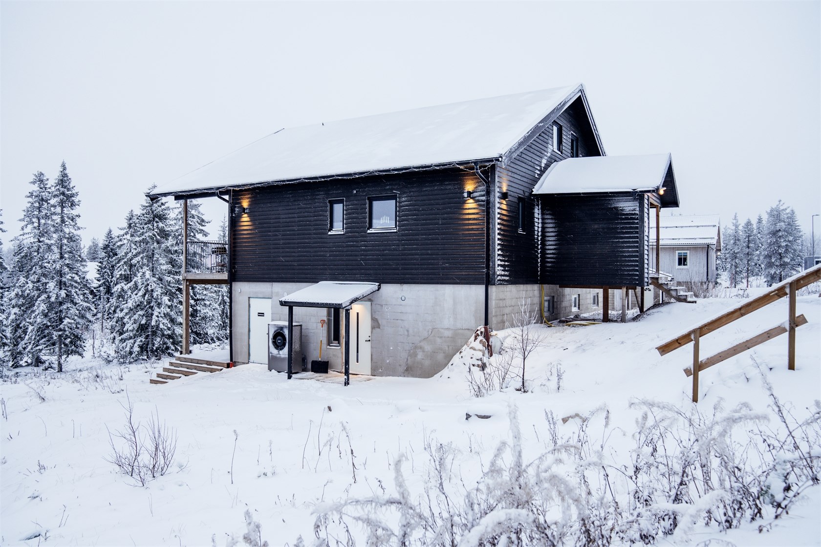 Modern trästuga i vintermiljö med snötäckt mark, stora fönster och träd i bakgrunden. Modern trästuga i vintermiljö med snötäckt mark, stora fönster och träd i bakgrunden.