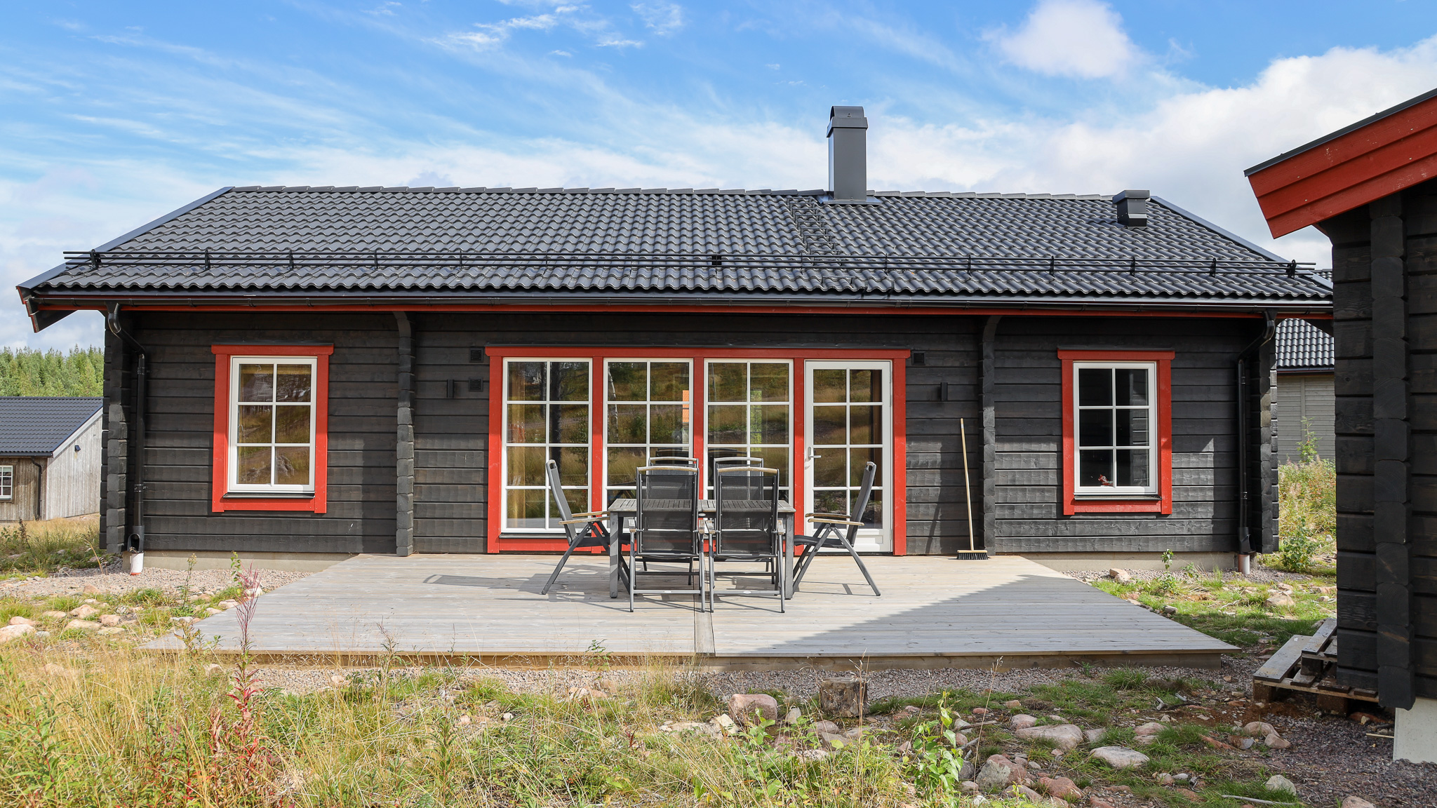 Mörk trästuga med röda fönsterluckor och altan framför entrén. Mörk trästuga med röda fönsterluckor och altan framför entrén.