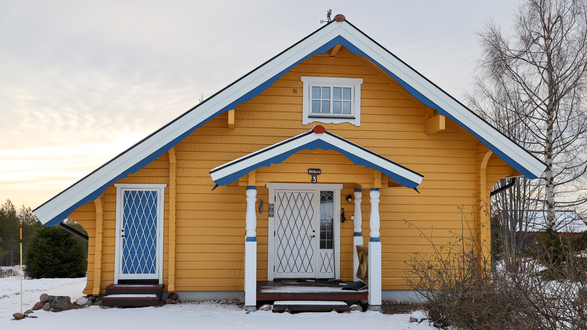 Gul byggnad med vit entré och snö på marken. Gul byggnad med vit entré och snö på marken.