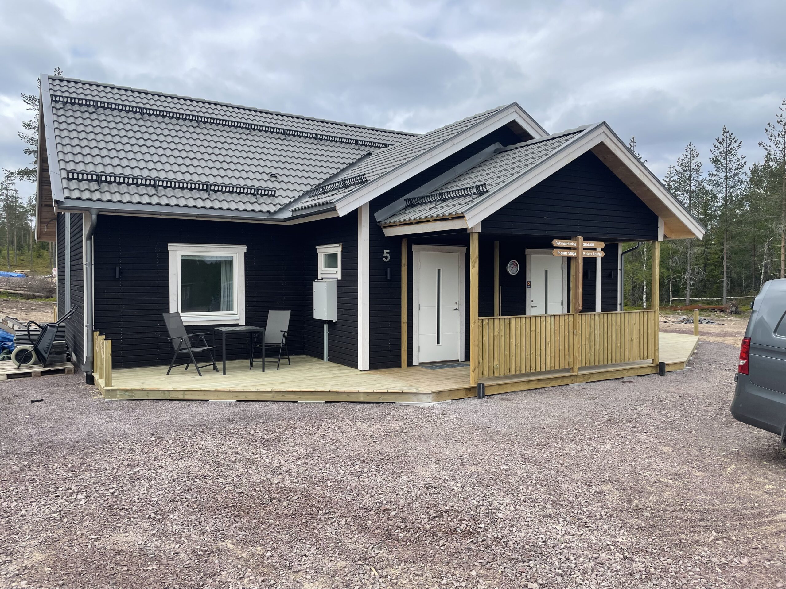 Modern stuga med mörk och ljus träfasad, entré på framsidan och grusad yta runt huset. Modern stuga med mörk och ljus träfasad, entré på framsidan och grusad yta runt huset.