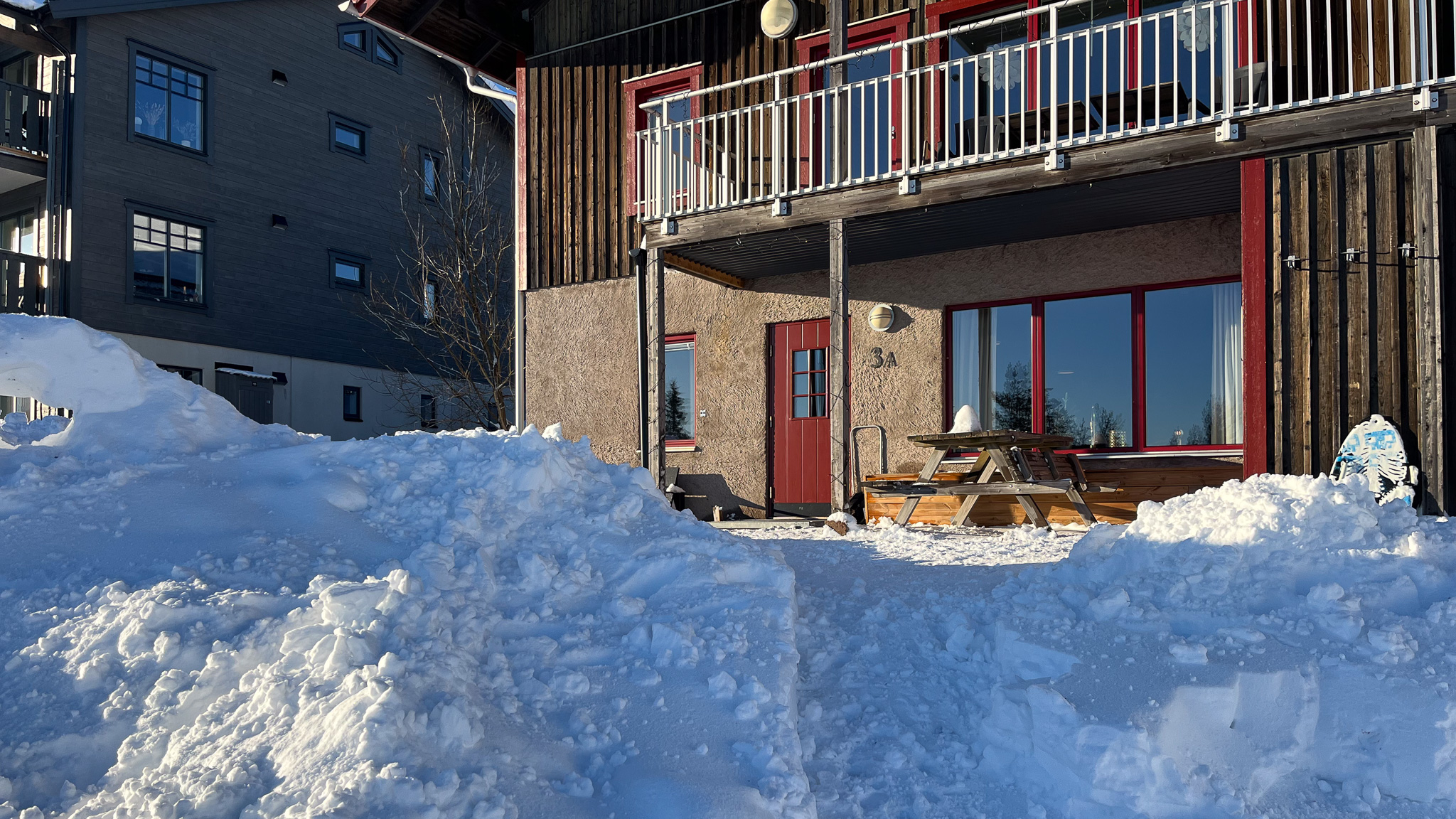 Flerbostadshus med balkonger och uteplatser i markplan, omgiven av snö. Flerbostadshus med balkonger och uteplatser i markplan, omgiven av snö.