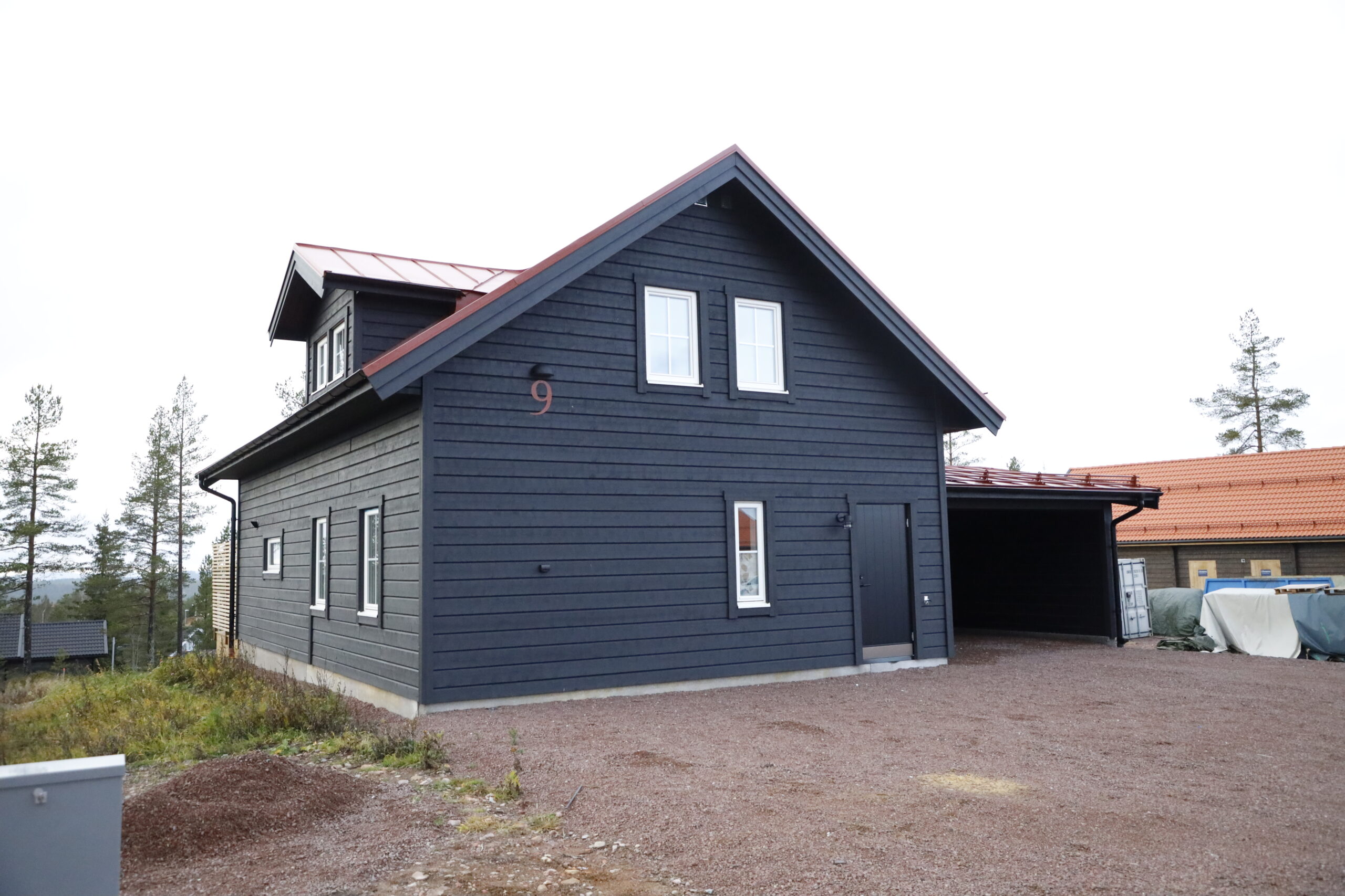 Mörk byggnad med sadeltak och grusyta framför. Mörk byggnad med sadeltak och grusyta framför.