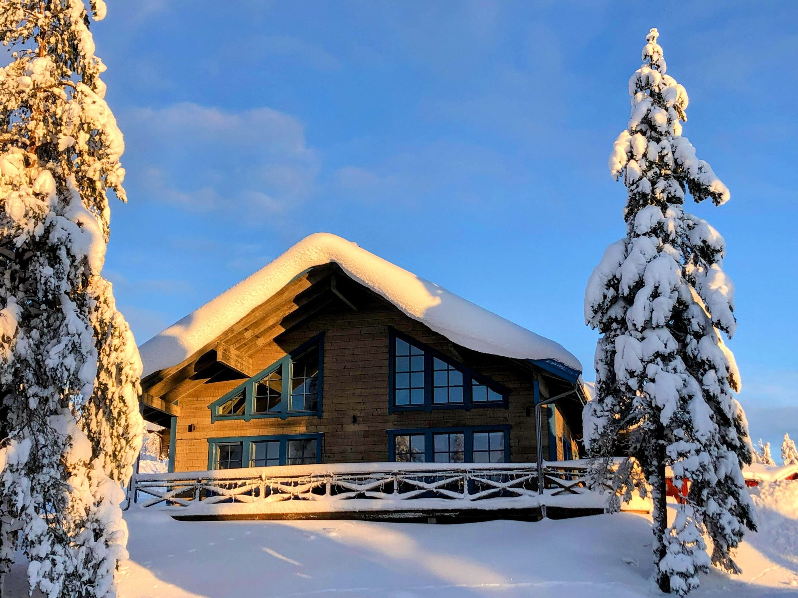 Timmerhus i snöigt landskap och blå himmel