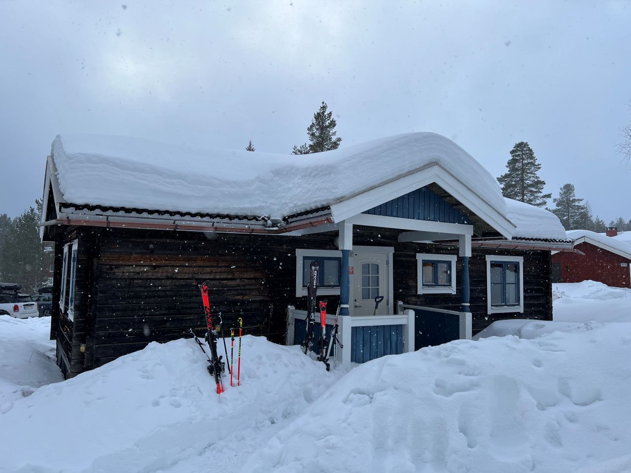 Trästuga i vintermiljö med snö runt huset, entré på framsidan