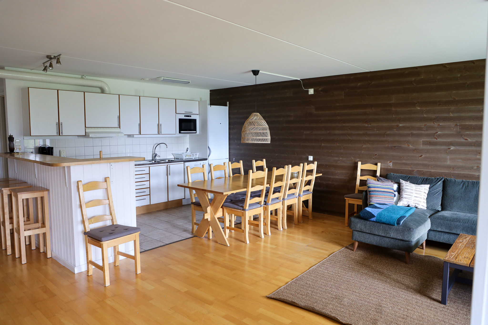 Vardagsrum och kök i öppen planlösning med matbord, soffa och köksö med vita skåp.