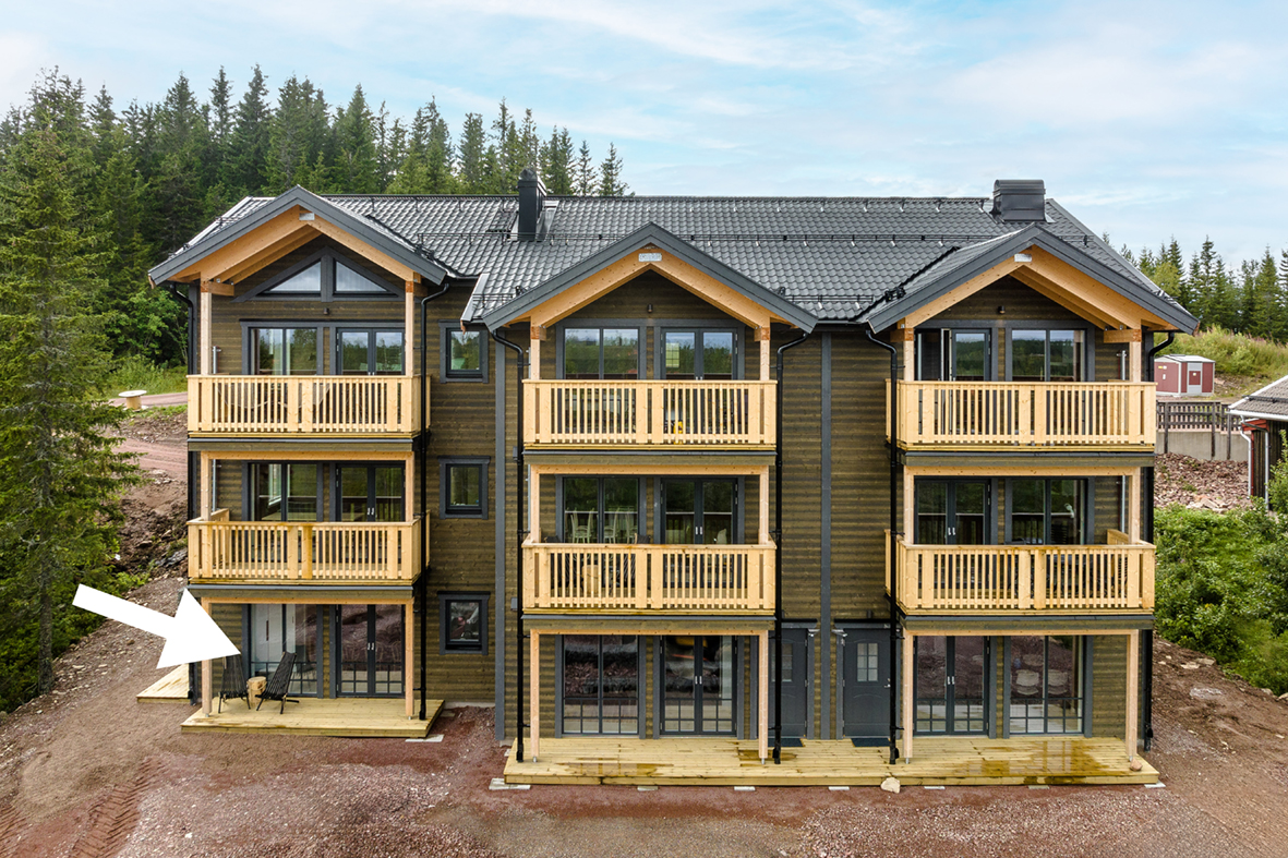 Flerbostadshus i tre våningar med balkonger och flera entréer.