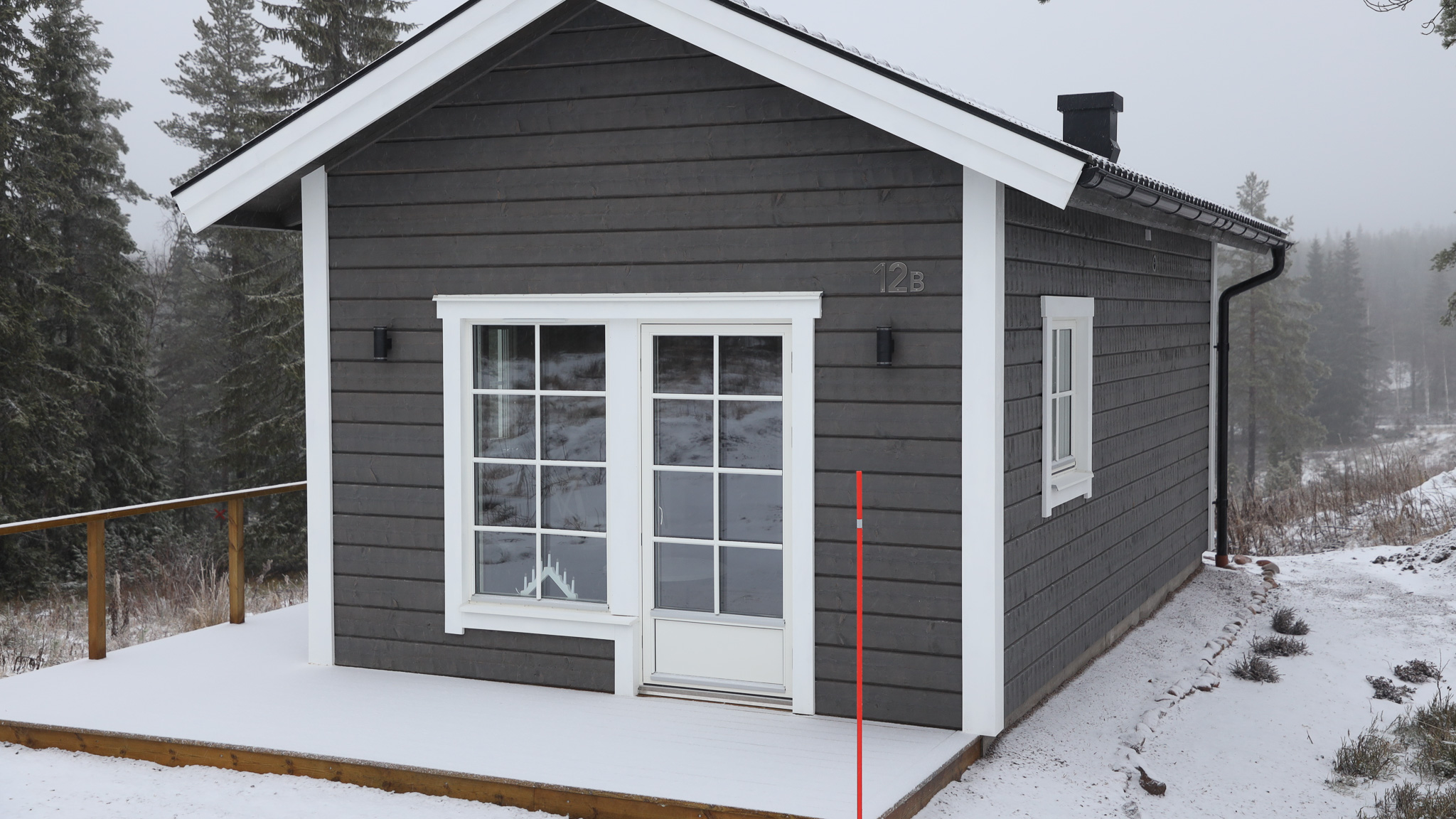 Mörk trästuga med dubbeldörrar och snötäckt mark runt byggnaden. Mörk trästuga med dubbeldörrar och snötäckt mark runt byggnaden.