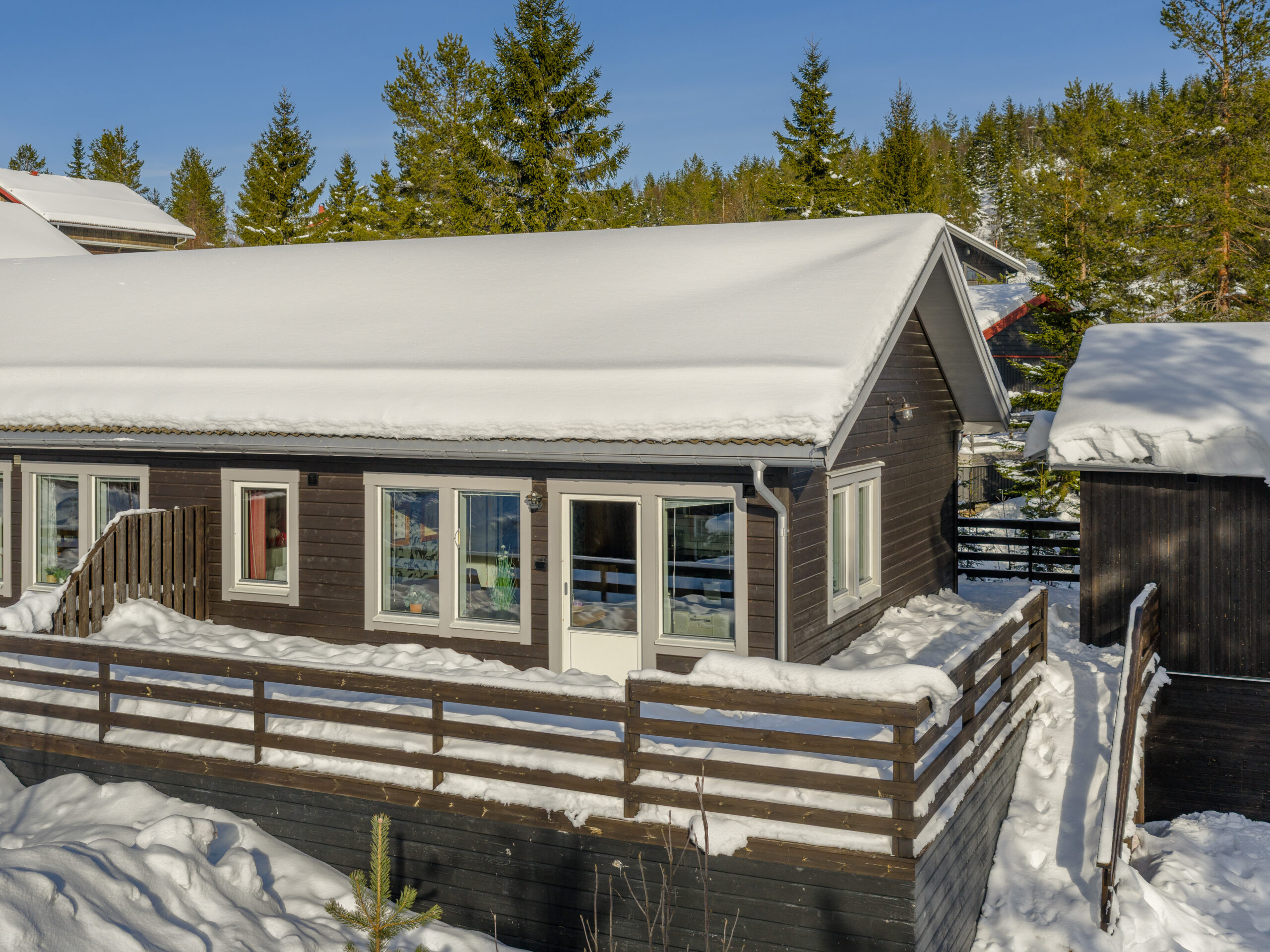 Ljus trästuga med veranda och snötäckt omgivning. Ljus trästuga med veranda och snötäckt omgivning.