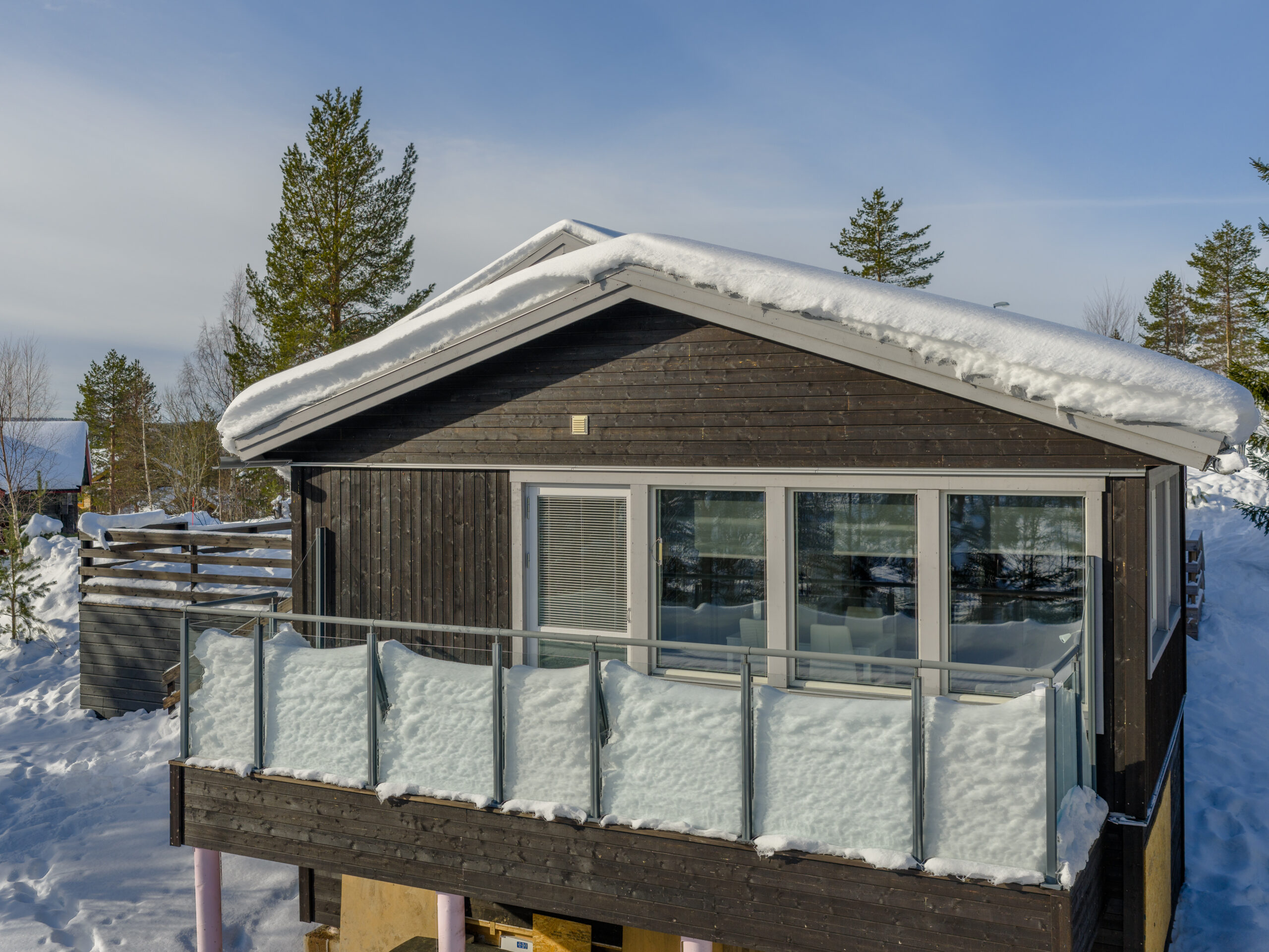 Trästuga med inglasad veranda och snötäckt tak i vintermiljö. Trästuga med inglasad veranda och snötäckt tak i vintermiljö.