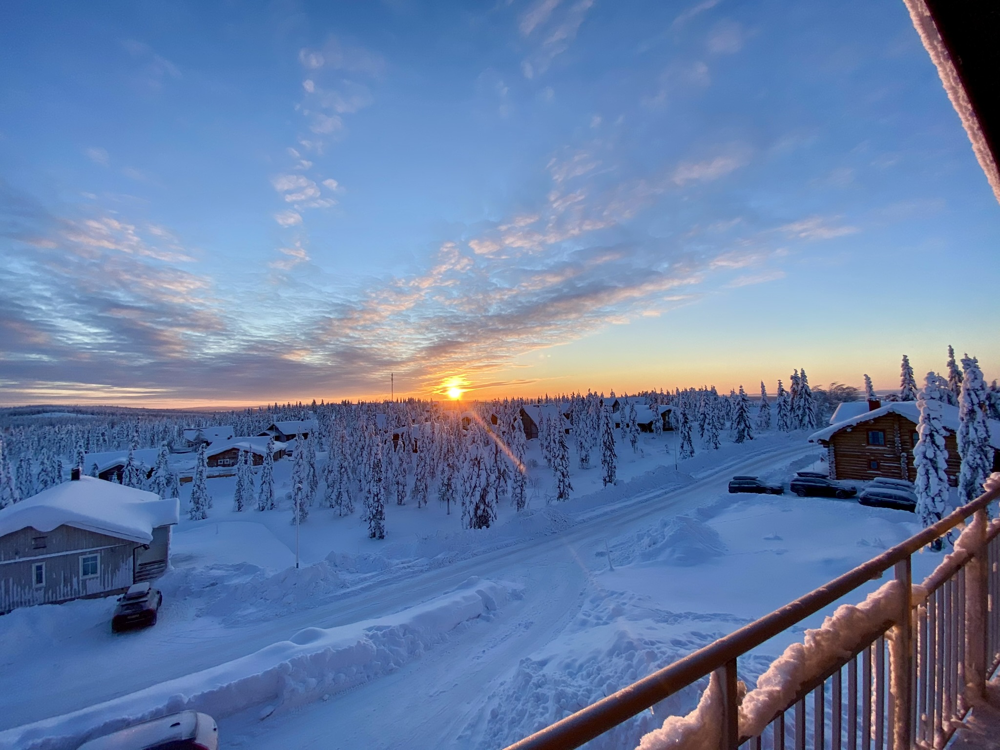 Solnedgång över snötäckt landskap sedd från veranda med räcke i förgrunden. Solnedgång över snötäckt landskap sedd från veranda med räcke i förgrunden.