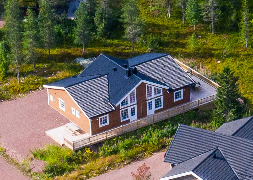 Flygbild över enplanshus med uteplats och omgivande grönska. Flygbild över enplanshus med uteplats och omgivande grönska.
