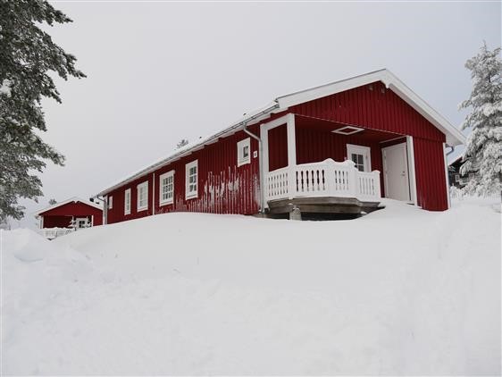 Röd byggnad med balkonger i snötäckt vintermiljö. Röd byggnad med balkonger i snötäckt vintermiljö.