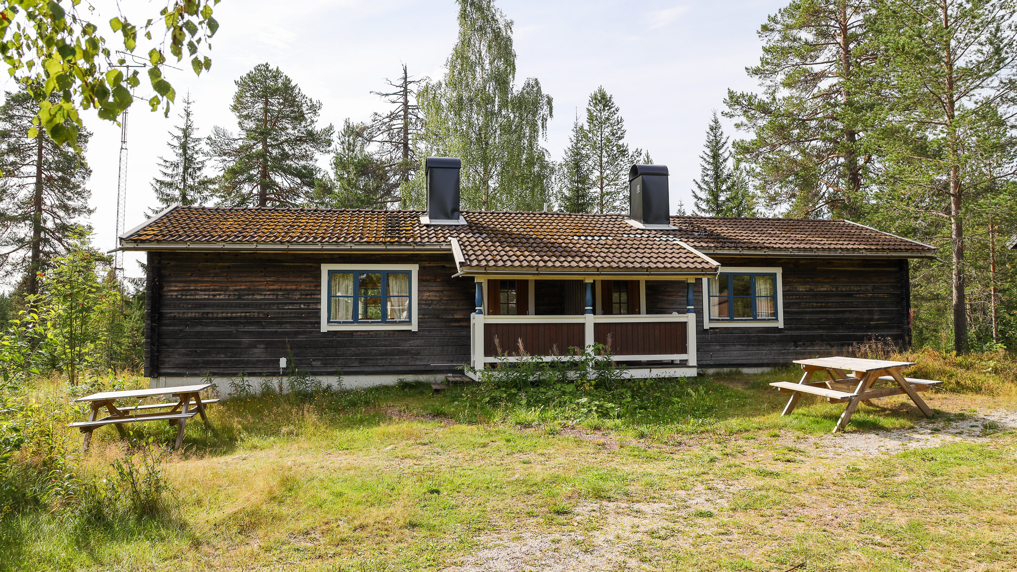 Trästuga med veranda, omgiven av skog och grönska. Trästuga med veranda, omgiven av skog och grönska.