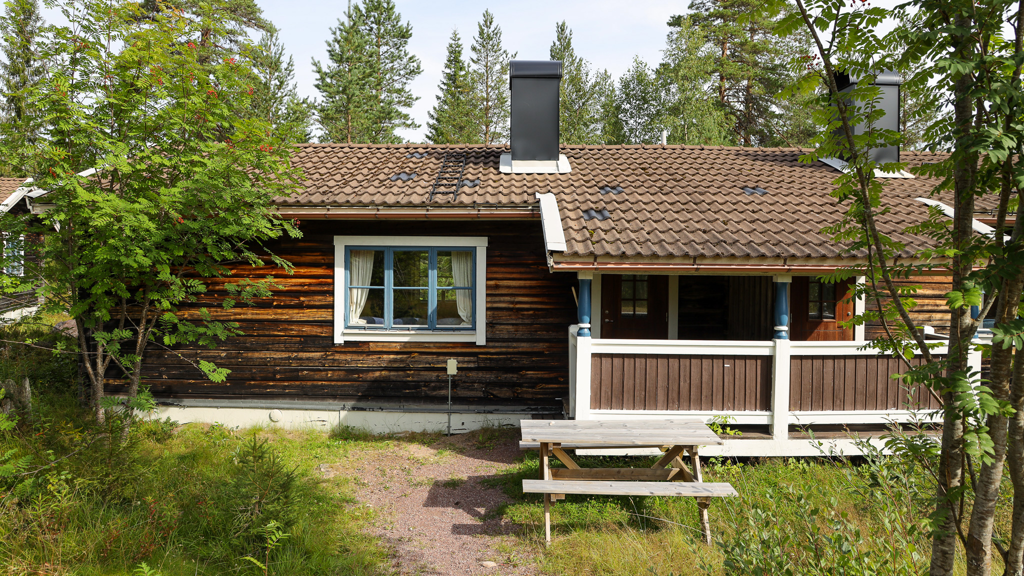 Trästuga med altan och stora fönster, omgiven av skog. Trästuga med altan och stora fönster, omgiven av skog.