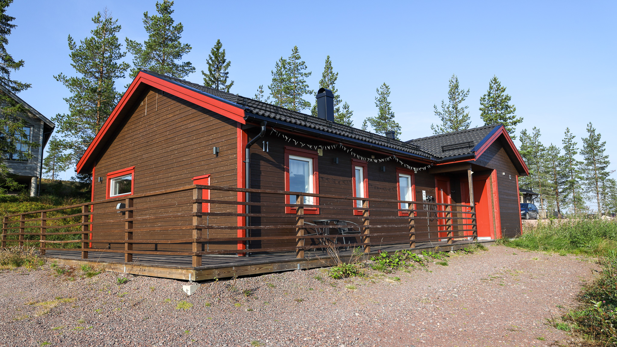 Röd trästuga med veranda och entré, omgiven av skog. Röd trästuga med veranda och entré, omgiven av skog.