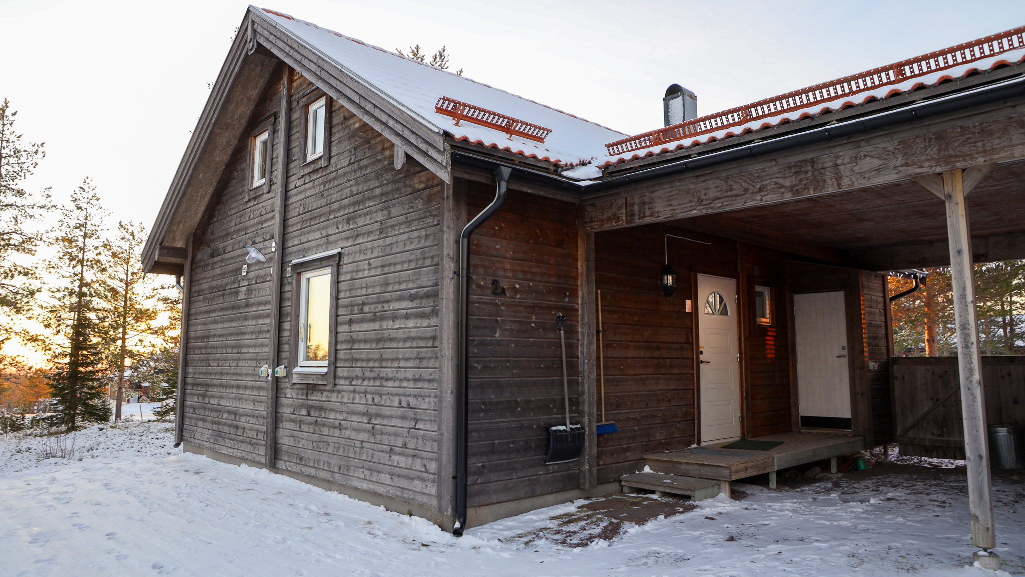 Trästuga med entré under tak och snö på marken. Trästuga med entré under tak och snö på marken.
