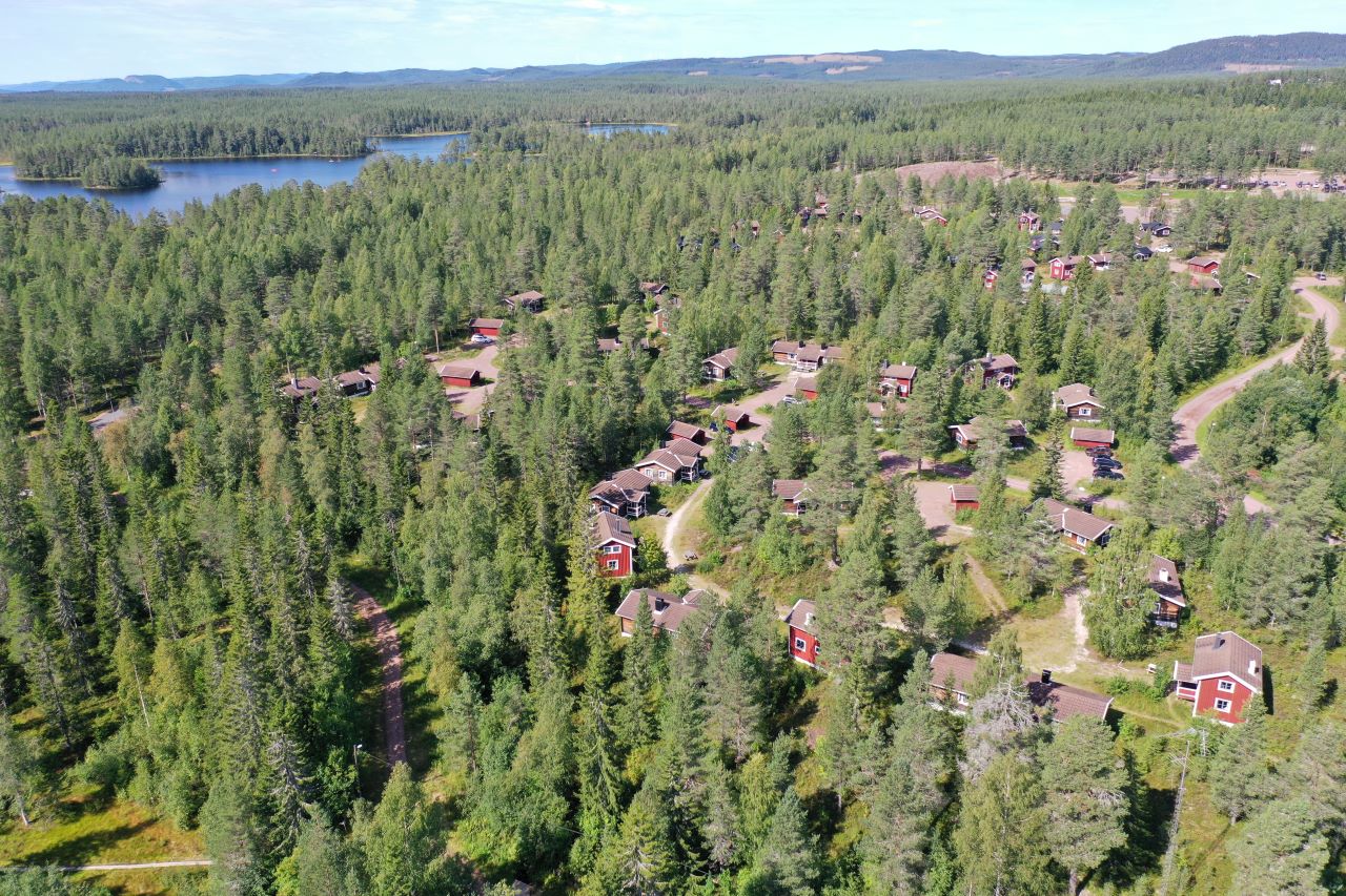 Flygvy över stugor utspridda i ett skogsområde. Flygvy över stugor utspridda i ett skogsområde.